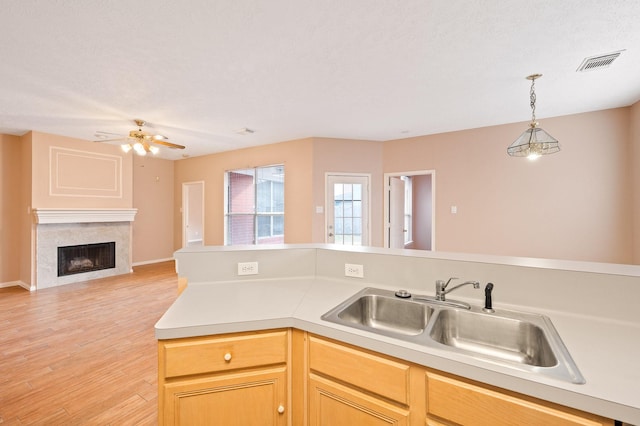 kitchen with sink, light hardwood / wood-style floors, hanging light fixtures, and light brown cabinets