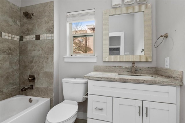 full bathroom featuring vanity, tiled shower / bath combo, and toilet