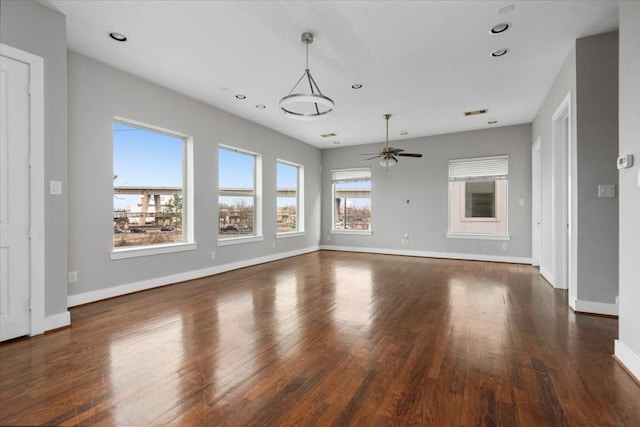 unfurnished living room with ceiling fan, a wealth of natural light, and dark hardwood / wood-style flooring