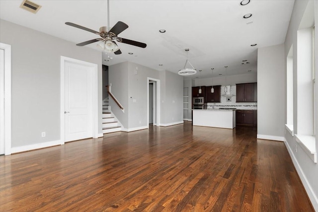 unfurnished living room featuring ceiling fan and dark hardwood / wood-style floors