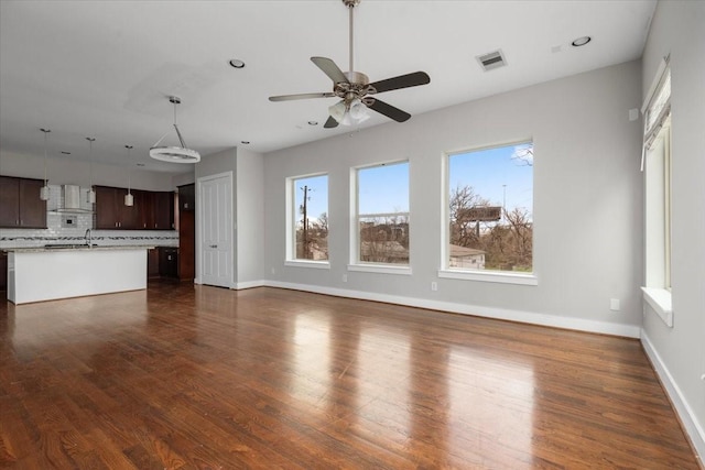 unfurnished living room featuring ceiling fan, sink, and dark hardwood / wood-style flooring