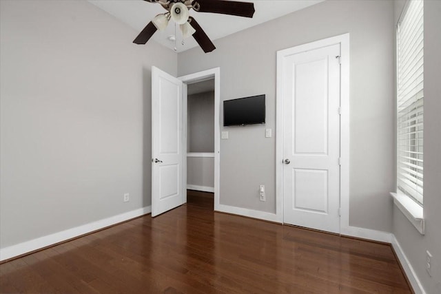 unfurnished bedroom featuring multiple windows, dark hardwood / wood-style floors, and ceiling fan