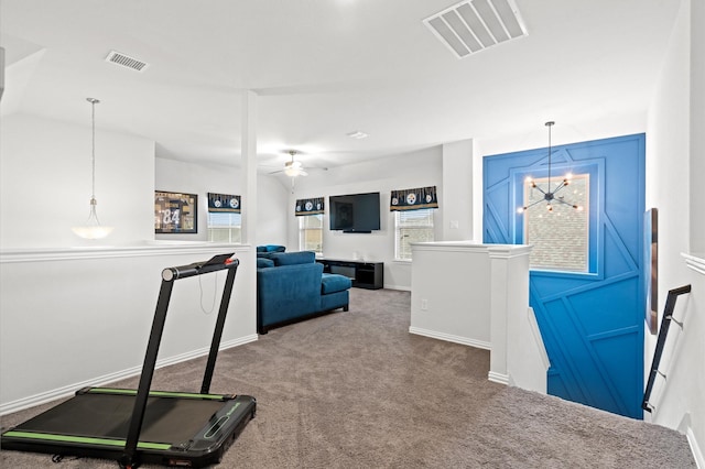 workout area with carpet flooring and ceiling fan with notable chandelier