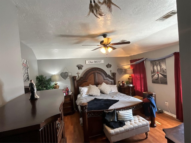 bedroom with ceiling fan, hardwood / wood-style flooring, and a textured ceiling