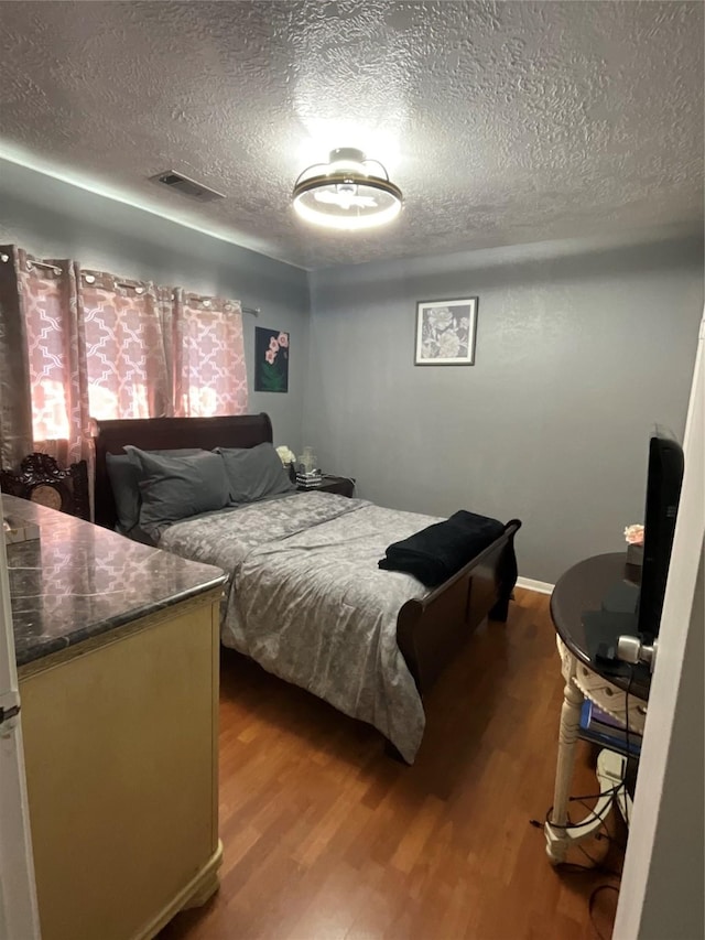 bedroom with hardwood / wood-style flooring and a textured ceiling