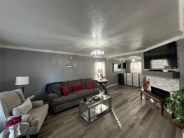 living room with hardwood / wood-style flooring, a fireplace, ornamental molding, and a textured ceiling