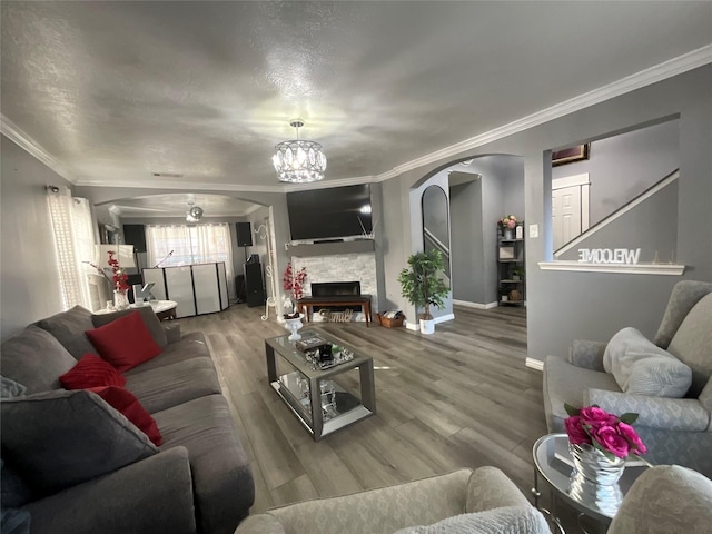 living room featuring wood-type flooring, crown molding, and a fireplace