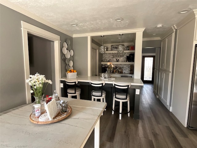 dining space with dark wood-type flooring, ornamental molding, and a textured ceiling