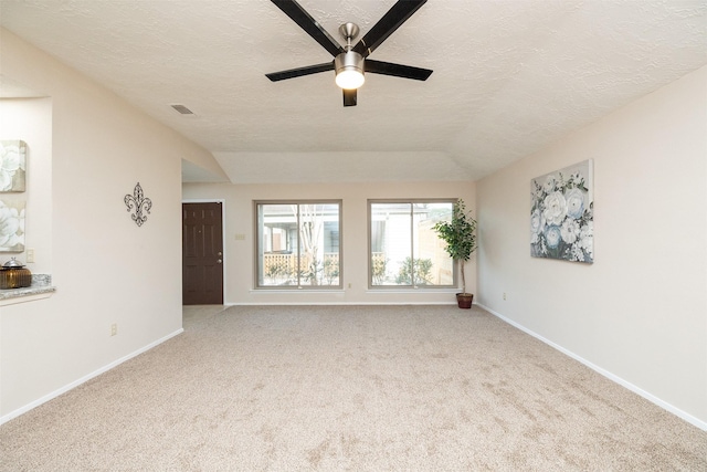 carpeted spare room with ceiling fan, vaulted ceiling, and a textured ceiling