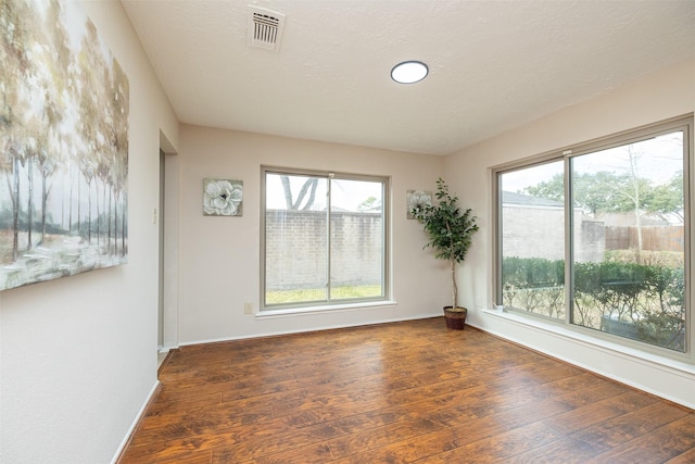 spare room with dark hardwood / wood-style floors and a textured ceiling