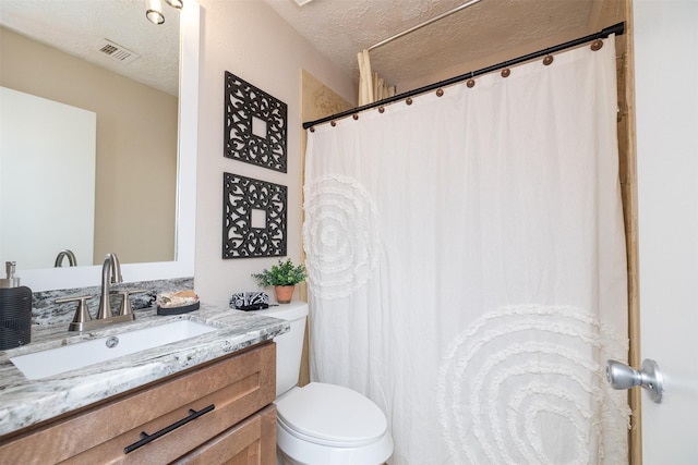 bathroom with vanity, a textured ceiling, and toilet