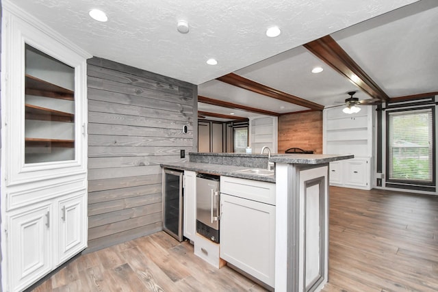 kitchen featuring white cabinetry, sink, wine cooler, and wood walls