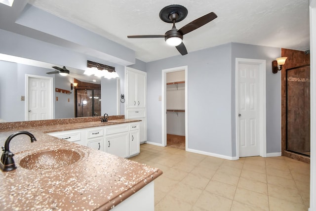 bathroom with a shower with shower door, a textured ceiling, vanity, ceiling fan, and tile patterned flooring