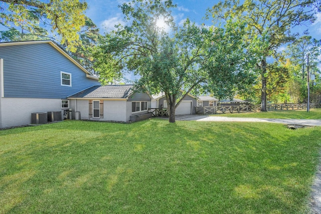 view of yard featuring central AC unit and a garage