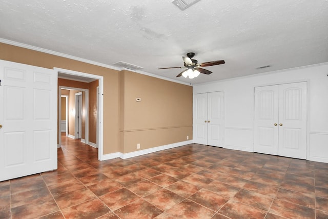 unfurnished bedroom with ceiling fan, a textured ceiling, ornamental molding, and multiple closets