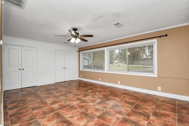 unfurnished bedroom featuring crown molding, two closets, ceiling fan, and a textured ceiling