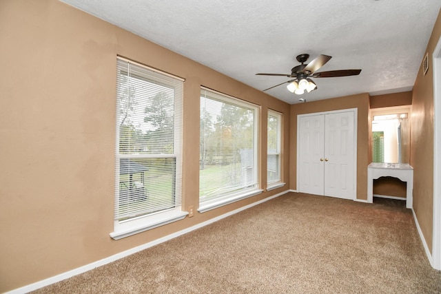 unfurnished bedroom featuring ceiling fan, carpet flooring, a textured ceiling, and a closet