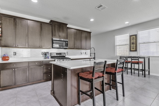 kitchen featuring appliances with stainless steel finishes, sink, a kitchen island with sink, and backsplash