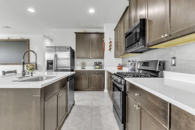 kitchen with sink, light tile patterned floors, stainless steel appliances, tasteful backsplash, and dark brown cabinetry