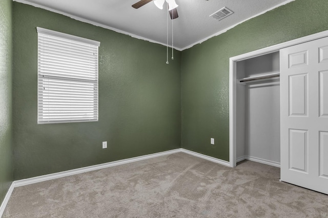 unfurnished bedroom featuring ornamental molding, light colored carpet, a closet, and ceiling fan