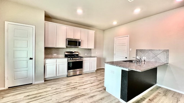 kitchen with white cabinetry, stainless steel appliances, kitchen peninsula, and light hardwood / wood-style floors