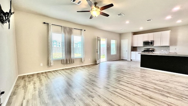 kitchen featuring white cabinetry, sink, stove, ceiling fan, and light hardwood / wood-style floors