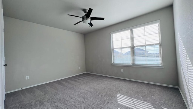 empty room with ceiling fan and dark carpet