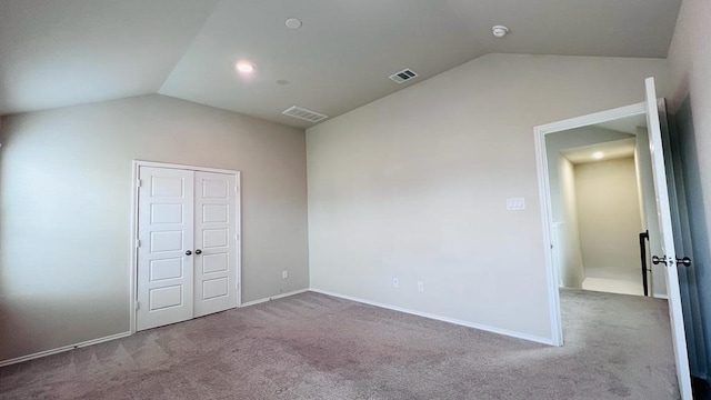 unfurnished bedroom with light colored carpet, lofted ceiling, and a closet