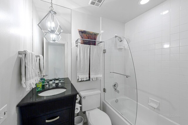 full bathroom with tiled shower / bath, vanity, and toilet