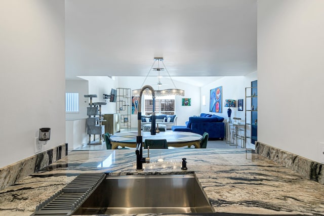 kitchen with hanging light fixtures, vaulted ceiling, and sink