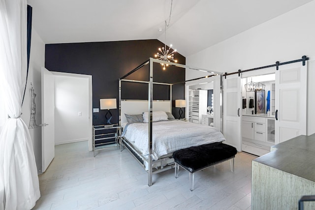 bedroom featuring light wood-type flooring, a barn door, vaulted ceiling, and a notable chandelier