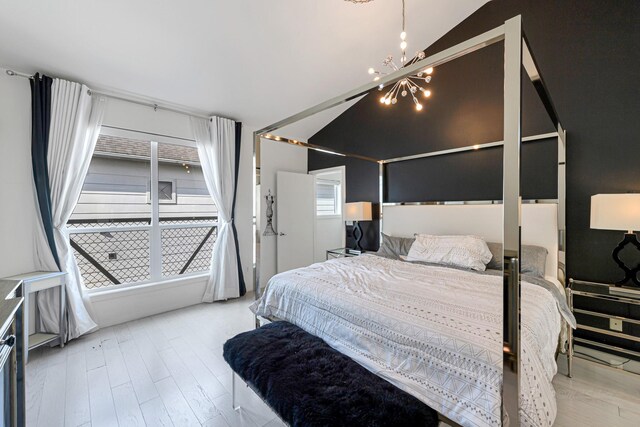 bedroom with lofted ceiling, a chandelier, and light hardwood / wood-style flooring