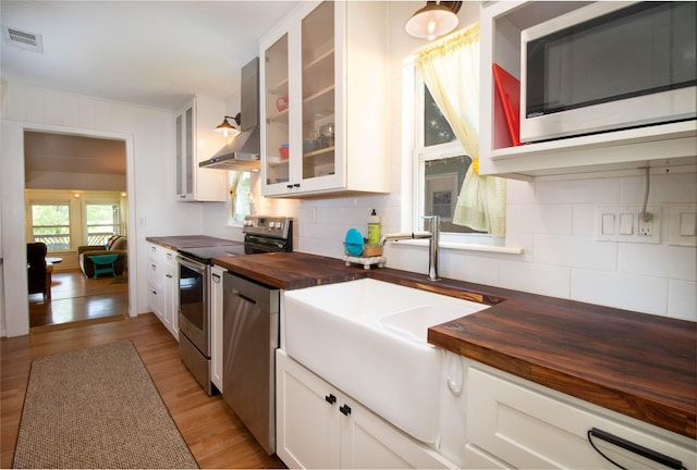 kitchen featuring tasteful backsplash, white cabinetry, butcher block counters, sink, and stainless steel appliances