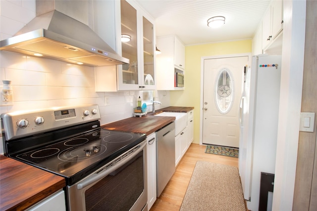 kitchen with island exhaust hood, wooden counters, white cabinets, and appliances with stainless steel finishes