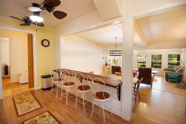 interior space with a breakfast bar area, light hardwood / wood-style floors, kitchen peninsula, and ceiling fan