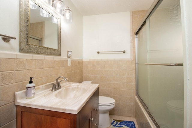 full bathroom featuring tile walls, shower / bath combination with glass door, tile patterned flooring, vanity, and toilet