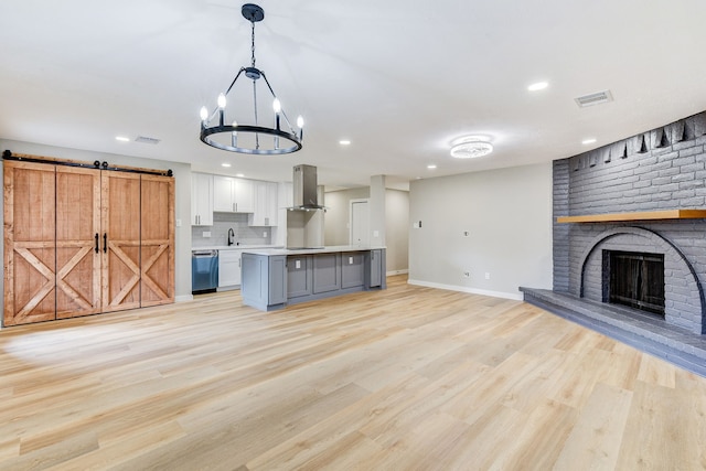 kitchen with pendant lighting, island exhaust hood, white cabinets, a kitchen island, and stainless steel dishwasher