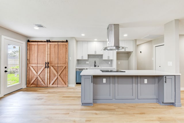 kitchen featuring sink, white cabinetry, island range hood, stainless steel dishwasher, and a barn door