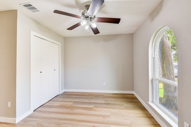 unfurnished bedroom featuring ceiling fan, light wood-type flooring, and a closet