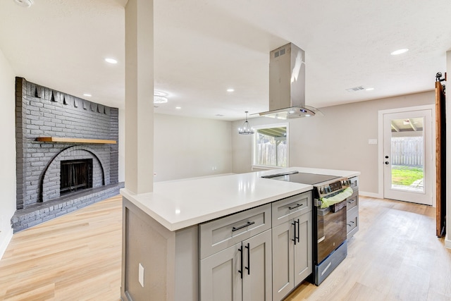 kitchen with gray cabinets, a kitchen island, island range hood, a fireplace, and stainless steel electric range