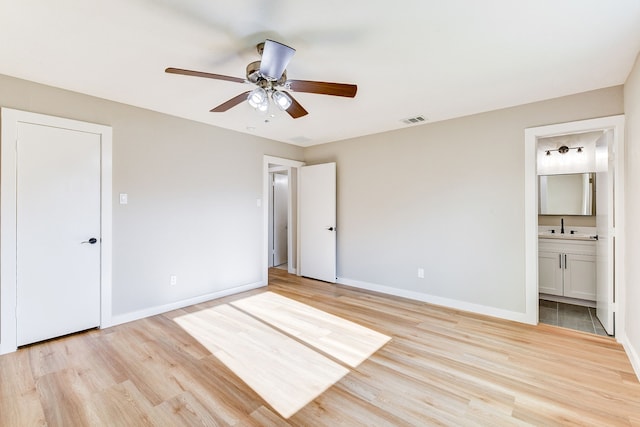 unfurnished bedroom with ceiling fan, sink, connected bathroom, and light wood-type flooring