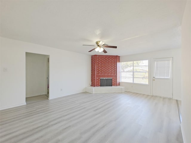 unfurnished living room with ceiling fan, light wood-type flooring, a textured ceiling, and a fireplace