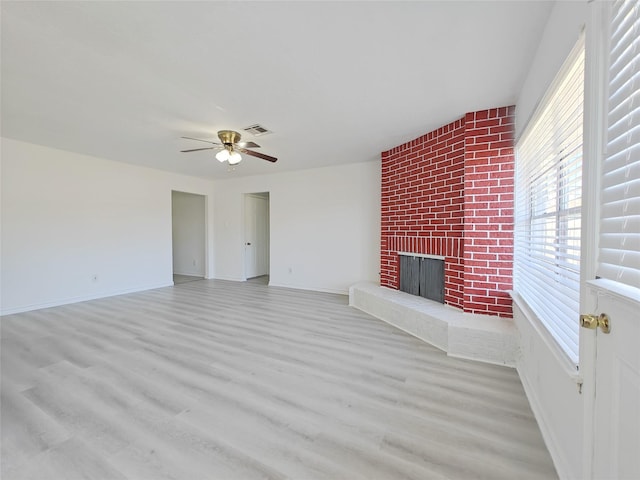 unfurnished living room featuring a brick fireplace, ceiling fan, and light hardwood / wood-style flooring