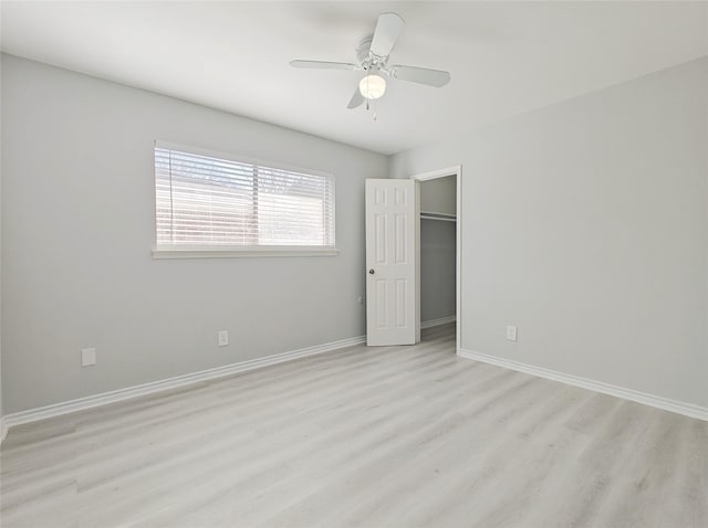 unfurnished bedroom featuring a walk in closet, light hardwood / wood-style floors, a closet, and ceiling fan