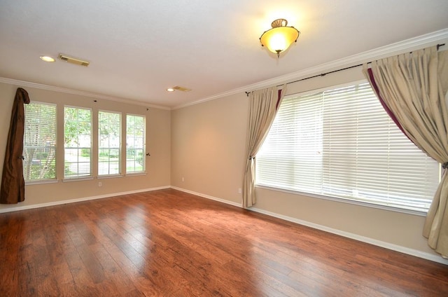 unfurnished room featuring baseboards, visible vents, dark wood finished floors, and ornamental molding