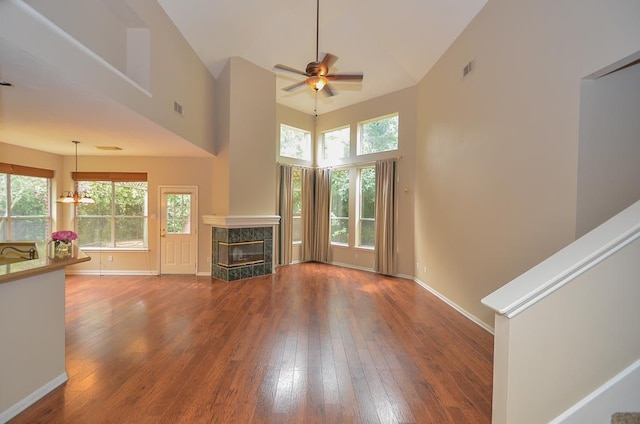 unfurnished living room featuring a premium fireplace, wood finished floors, visible vents, and a healthy amount of sunlight