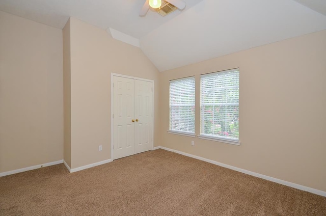 carpeted spare room featuring a ceiling fan, visible vents, vaulted ceiling, and baseboards