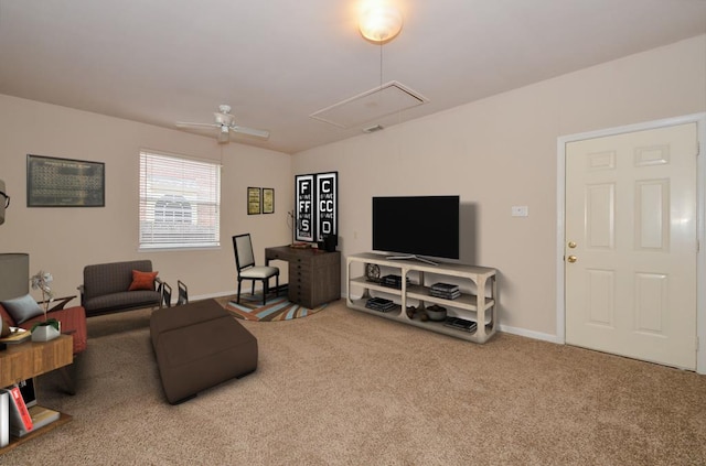 carpeted living area featuring attic access, baseboards, and a ceiling fan