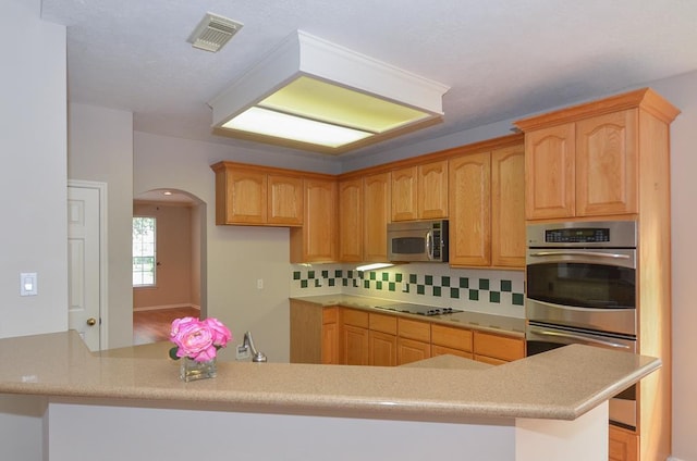 kitchen with stainless steel appliances, arched walkways, light countertops, and visible vents