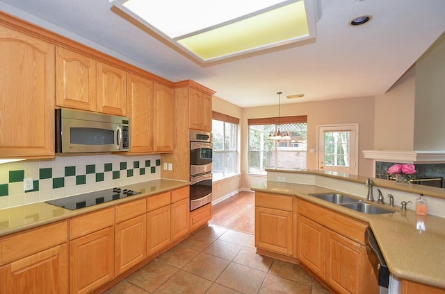 kitchen with appliances with stainless steel finishes, light countertops, a sink, and decorative light fixtures